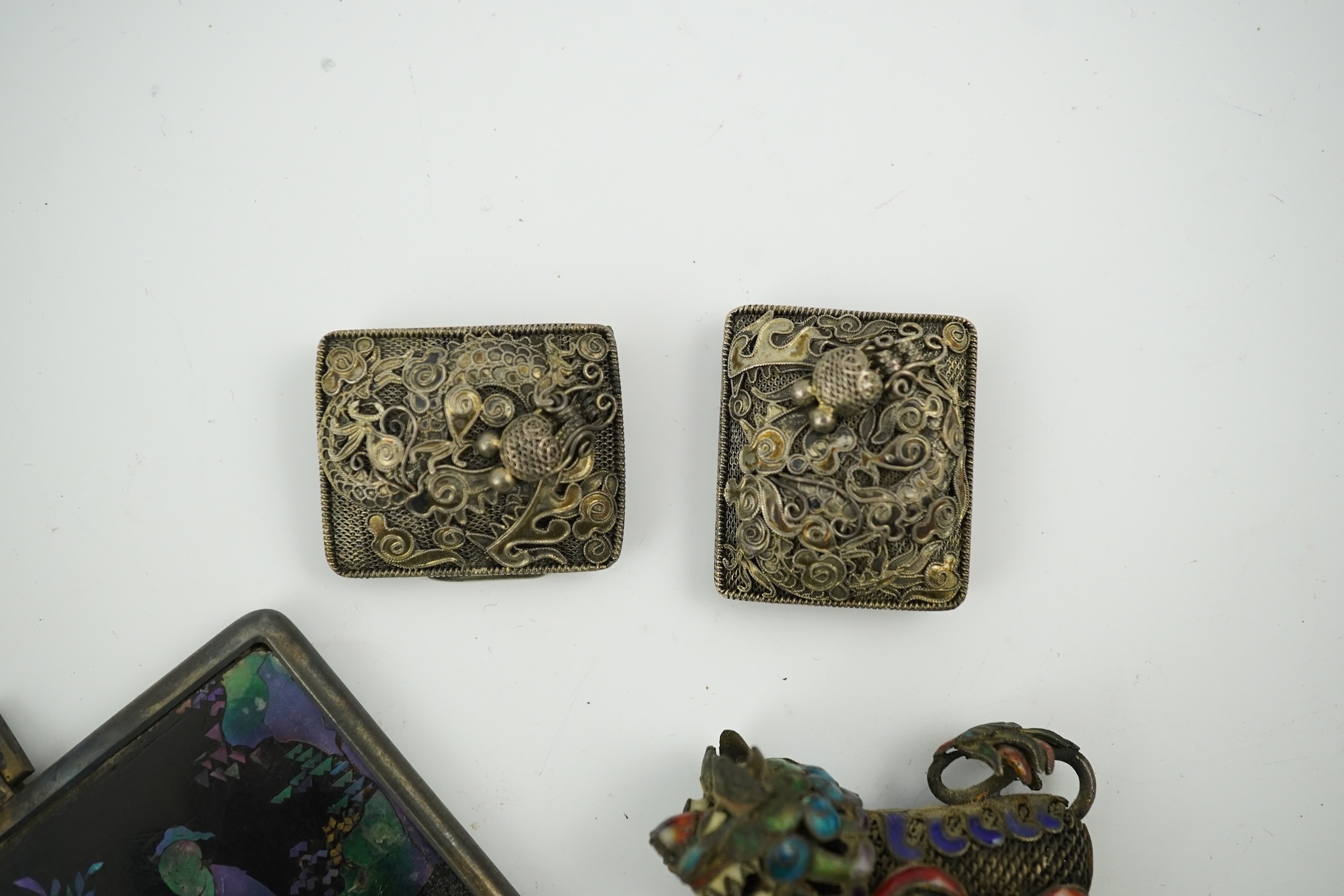 A Chinese silver buckle with filligree butterfly decoration, a pair of enamelled miniature lion dogs with balls and a small lac burgaute panel. Lion dogs 4.5cm long. Condition - good